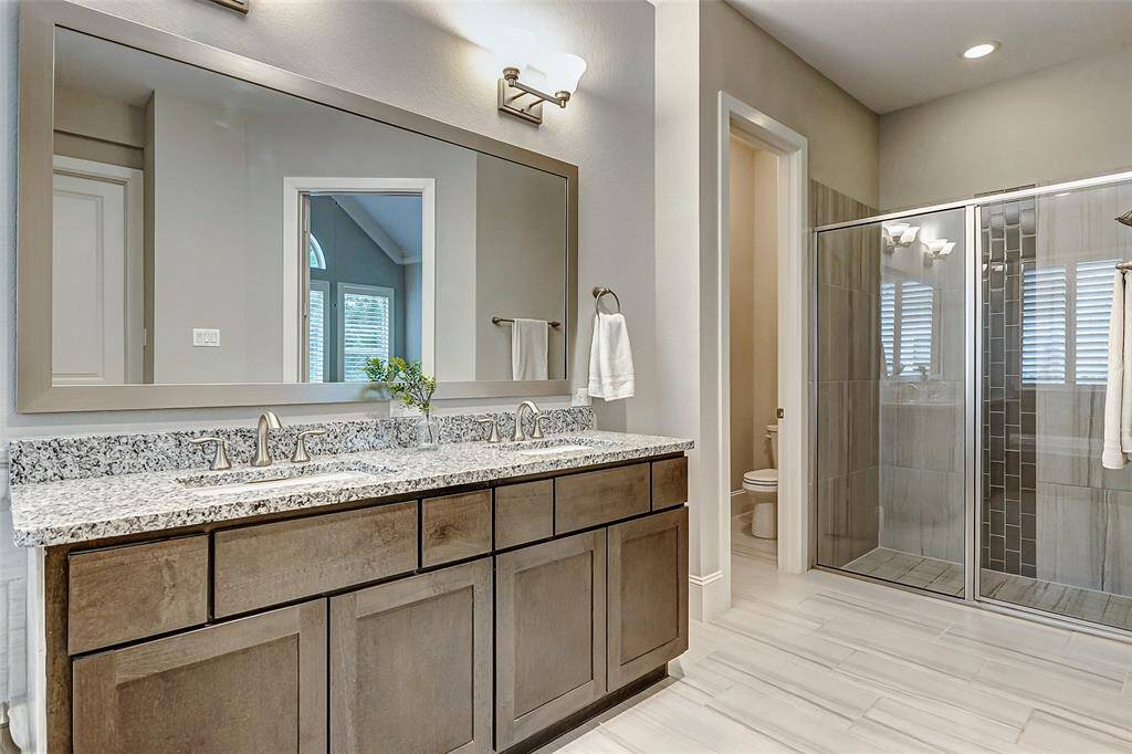 To the right of the vanity, you'll find a spacious walk-in shower with a sleek glass enclosure, offering a modern, open feel. The commode is thoughtfully tucked away for added privacy, enhancing the overall sense of serenity in the ensuite.