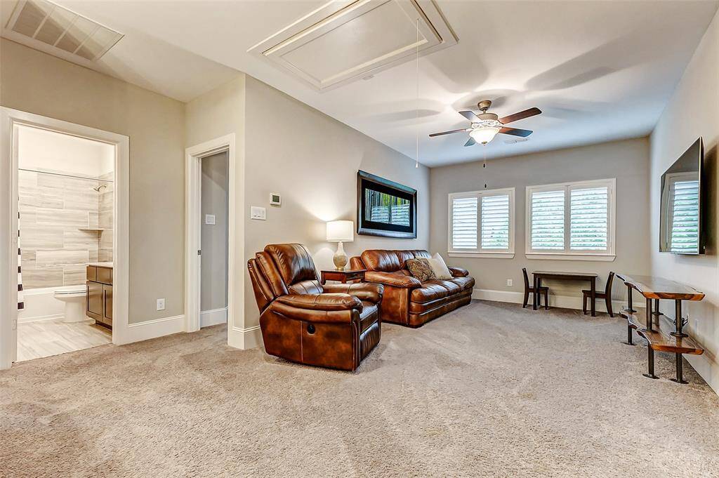 At the top of the stairs, you're welcomed by a spacious game room featuring plush carpeting, large windows with plantation shutters, and a ceiling fan for added comfort. This versatile space is perfect for relaxing, entertaining, or creating a fun retreat for family and friends.