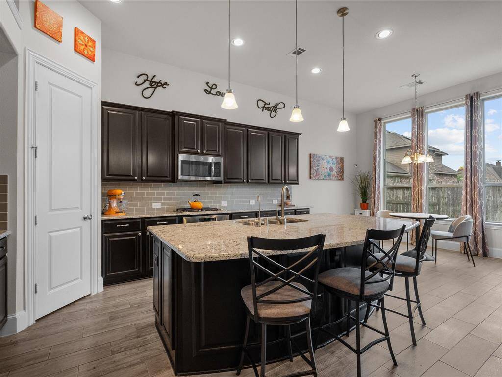 The kitchen has granite countertops, modern backsplash, and Maple-Espresso stained wood cabinetry.