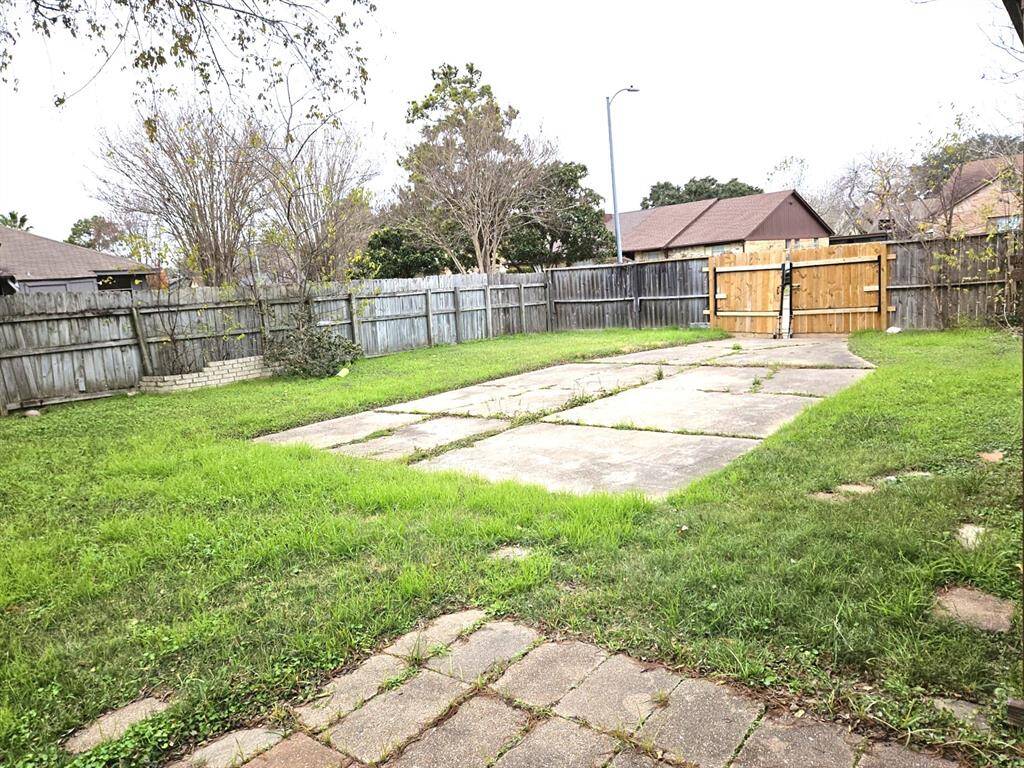 Spacious backyard with secure fencing and convenient double gates.