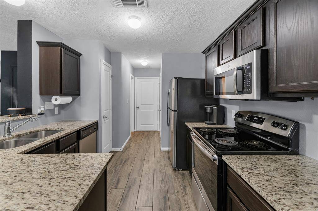 Additional view of the kitchen showing the granite counter tops and stainless steel appliances. The garage entry, pantry, and powder bath are seen in this view!