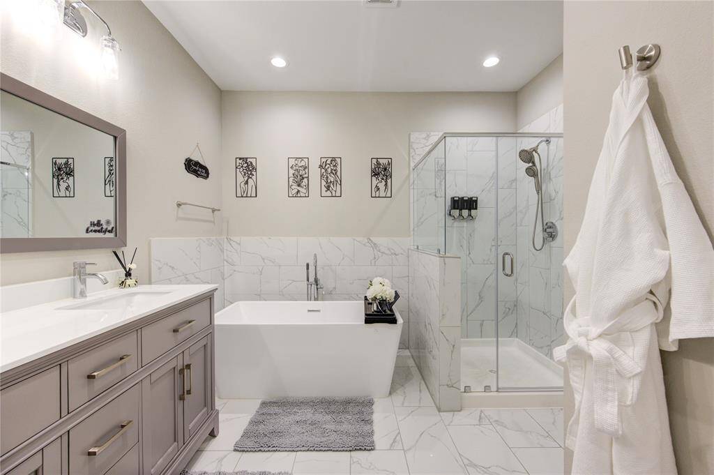 This bathroom features a modern design with a sleek freestanding bathtub and a glass-enclosed shower.