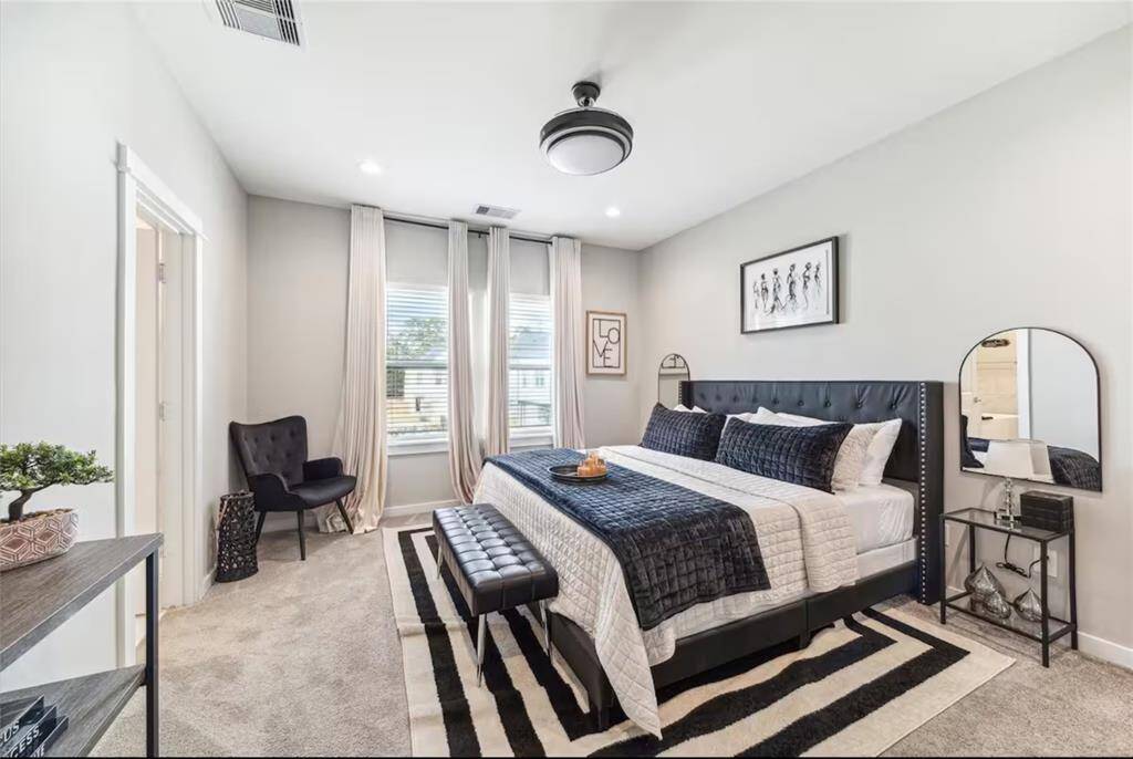 This master bedroom features ample natural light from a wide window, creating a comfortable and elegant space.