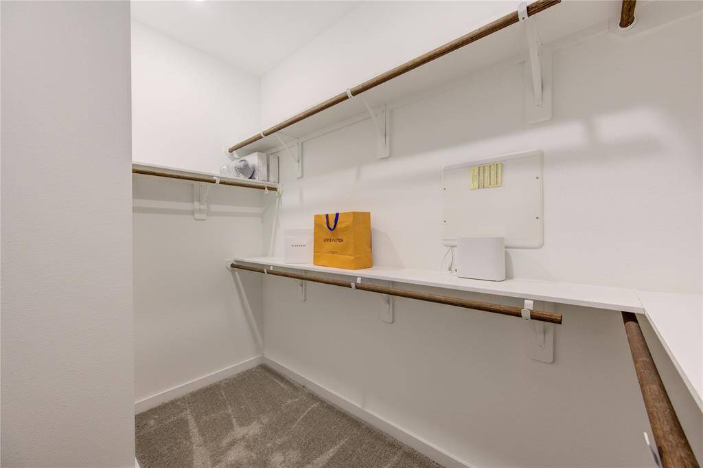 This photo shows a spacious walk-in closet with shelves and rods for ample storage.