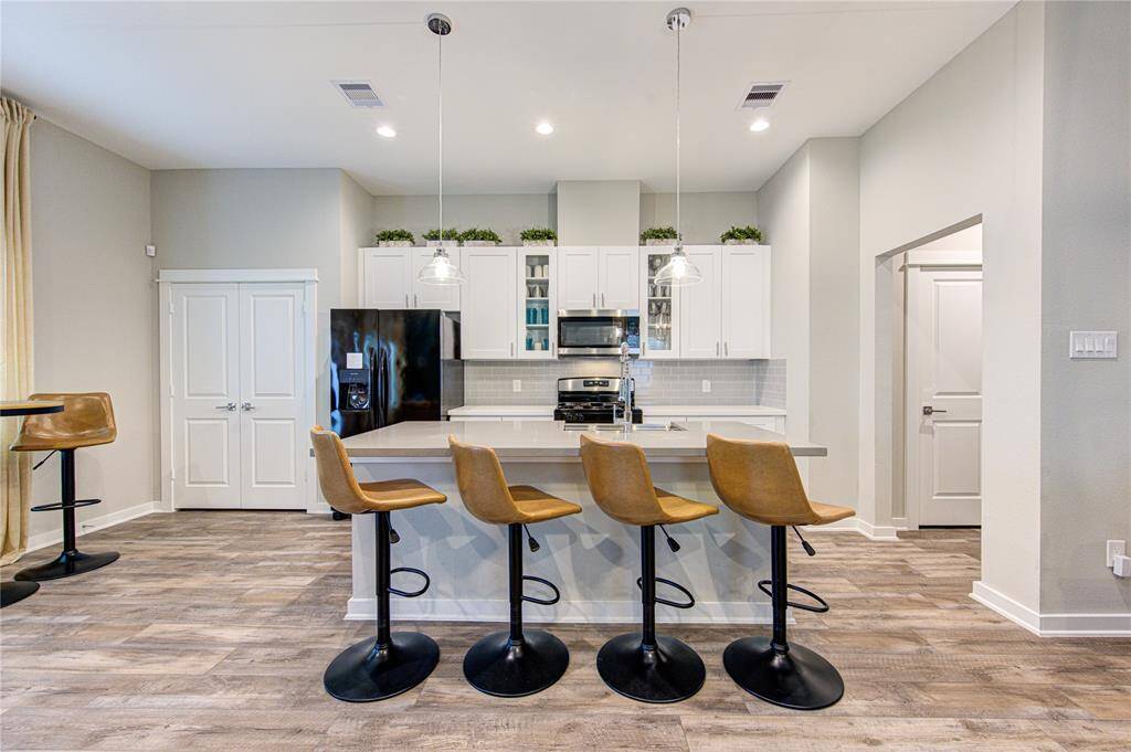 This modern kitchen features a sleek design with white cabinetry, stainless steel appliances, and a stylish island with bar seating. The open layout and neutral tones create a welcoming and functional space for cooking and entertaining.