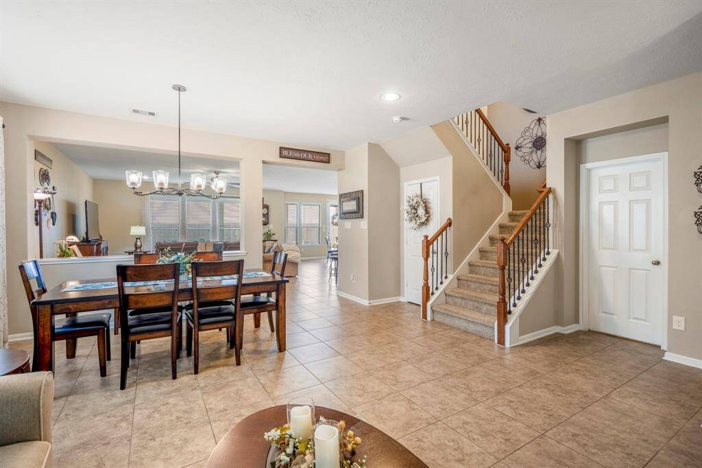 This inviting home features a spacious open-plan layout with a tiled floor, a cozy dining area, and a comfortable living space. The staircase adds charm, leading to the upper level. Neutral tones and ample natural light create a warm, welcoming atmosphere.