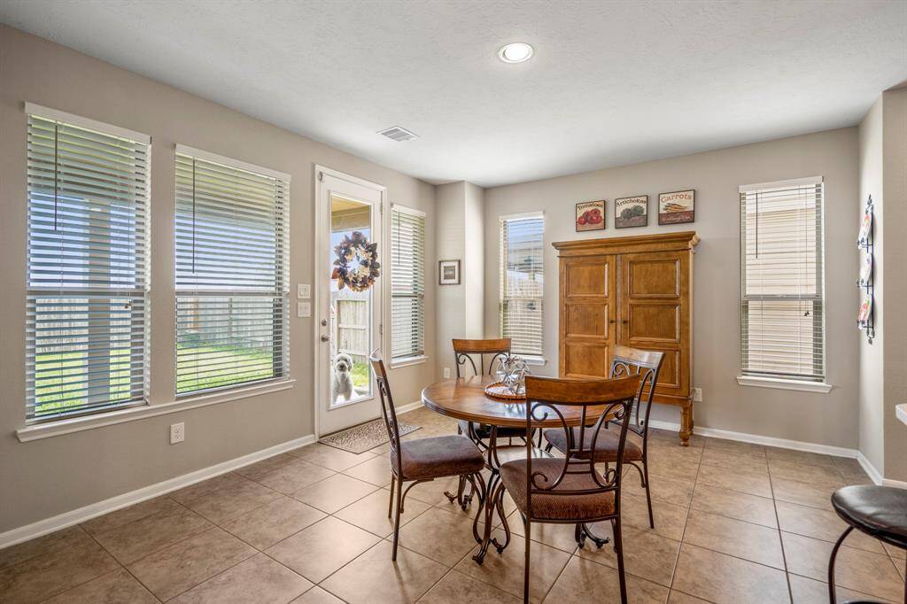 Bright dining area with large windows, tile flooring, and a door leading to the backyard.