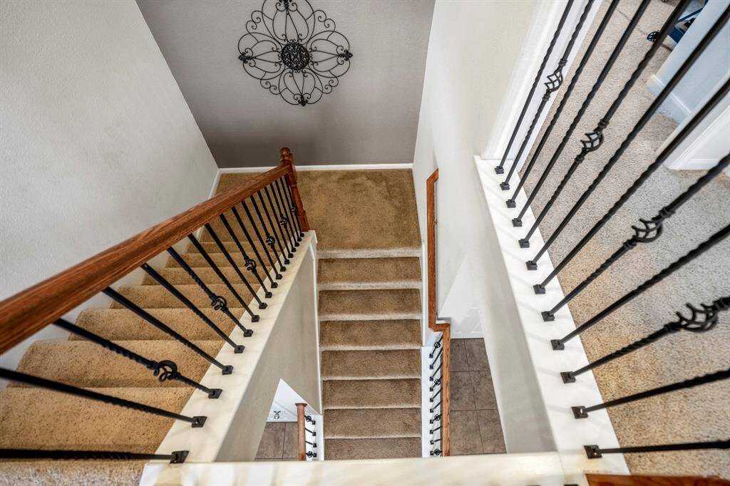 Staircase with carpeted steps and elegant wrought iron railings.