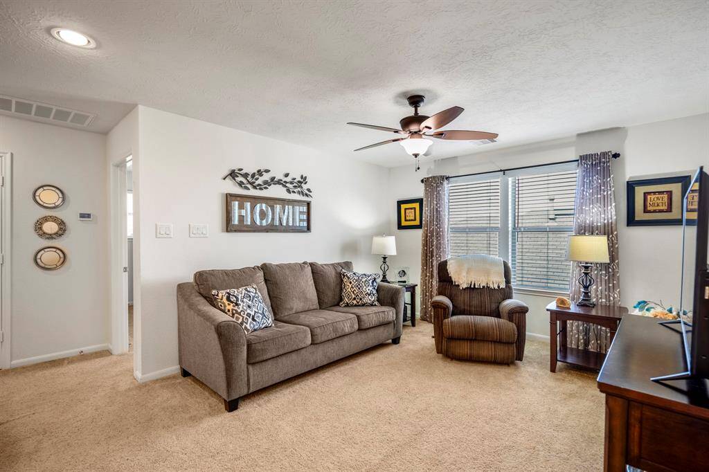 Cozy game room up stairs. A ceiling fan provides airflow, and large windows allow natural light.