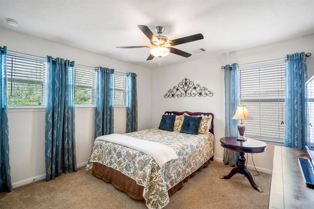 Cozy bedroom with ample natural light, featuring a ceiling fan light combo.