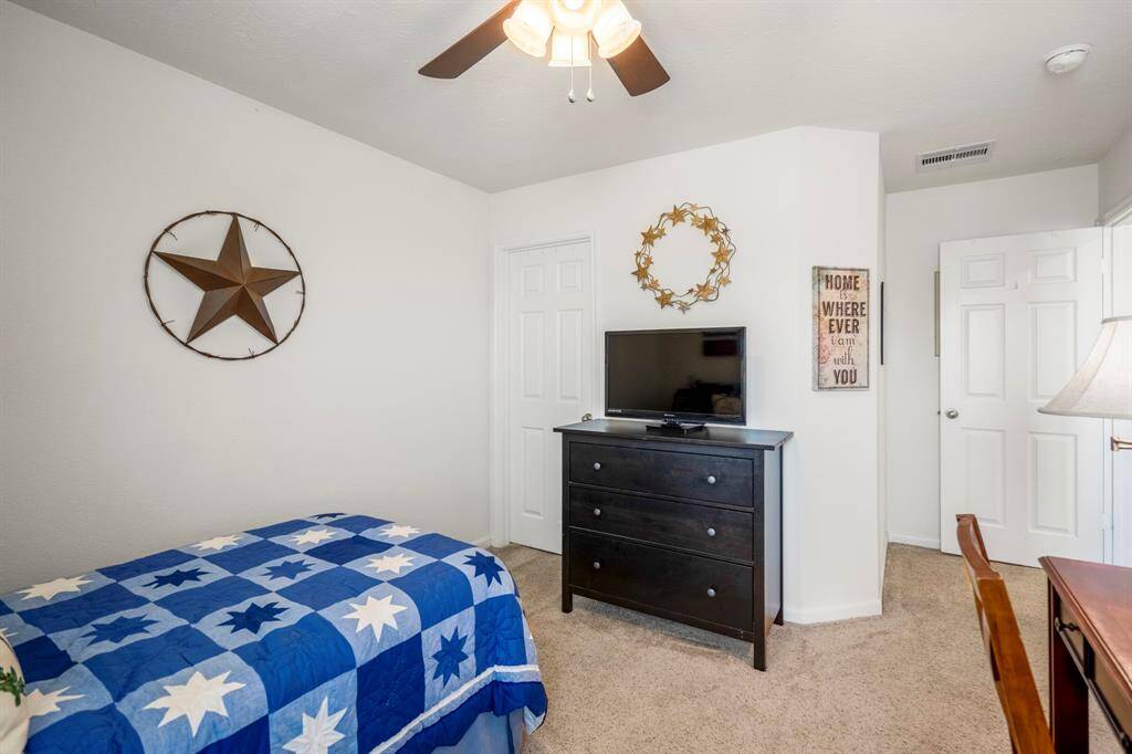 The room is carpeted and well-lit with a ceiling fan.