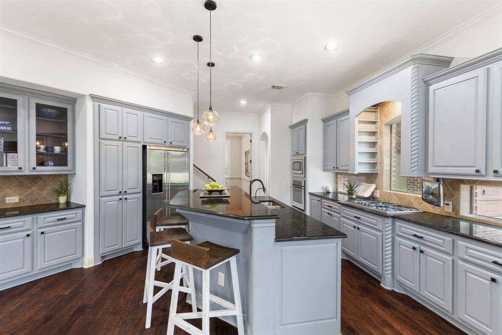 Top-of-the-line stainless steel GE Monogram appliances include a double-door refrigerator, built-in microwave, electric oven, 5-burner gas cooktop, and dishwasher. The kitchen also features recessed lighting, an oversized walk-in pantry (9 feet long!) and split landing staircase for direct access.