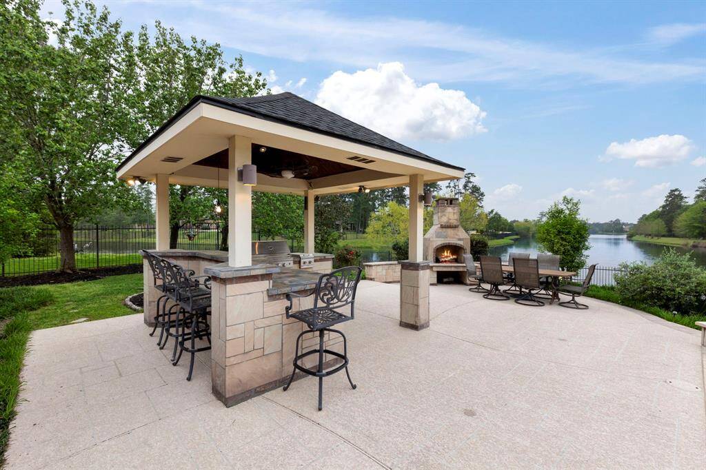A separate covered outdoor kitchen, with a stained bead board ceiling, offers everything you need to host unforgettable gatherings. Whether you're grilling on game day or enjoying evening cocktails by the water, this backyard is the ultimate retreat for entertaining year-round.