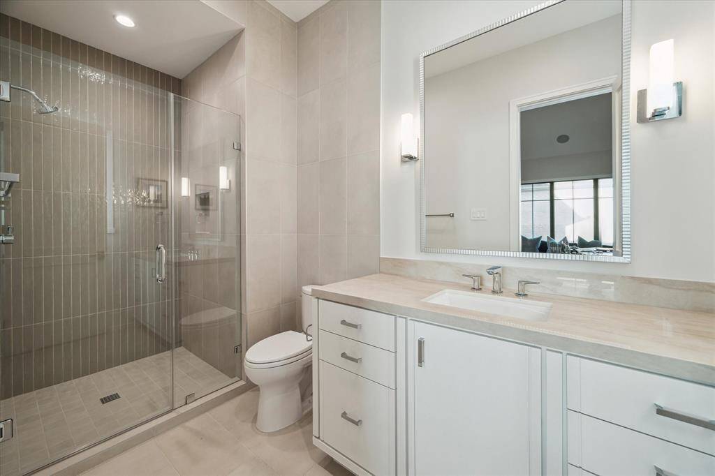 Guest bathroom #4 features a sleek quartzite vanity, brushed nickel fixtures, and a seamless glass walk-in shower. The room's clean lines and elegant finishes maximize comfort and function.