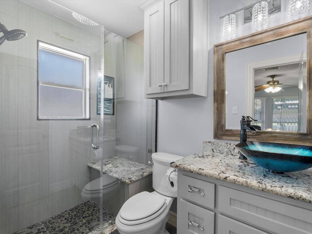 This en-suite bathroom has a large walk-in shower, upgraded cabinetry, and a wash basin.