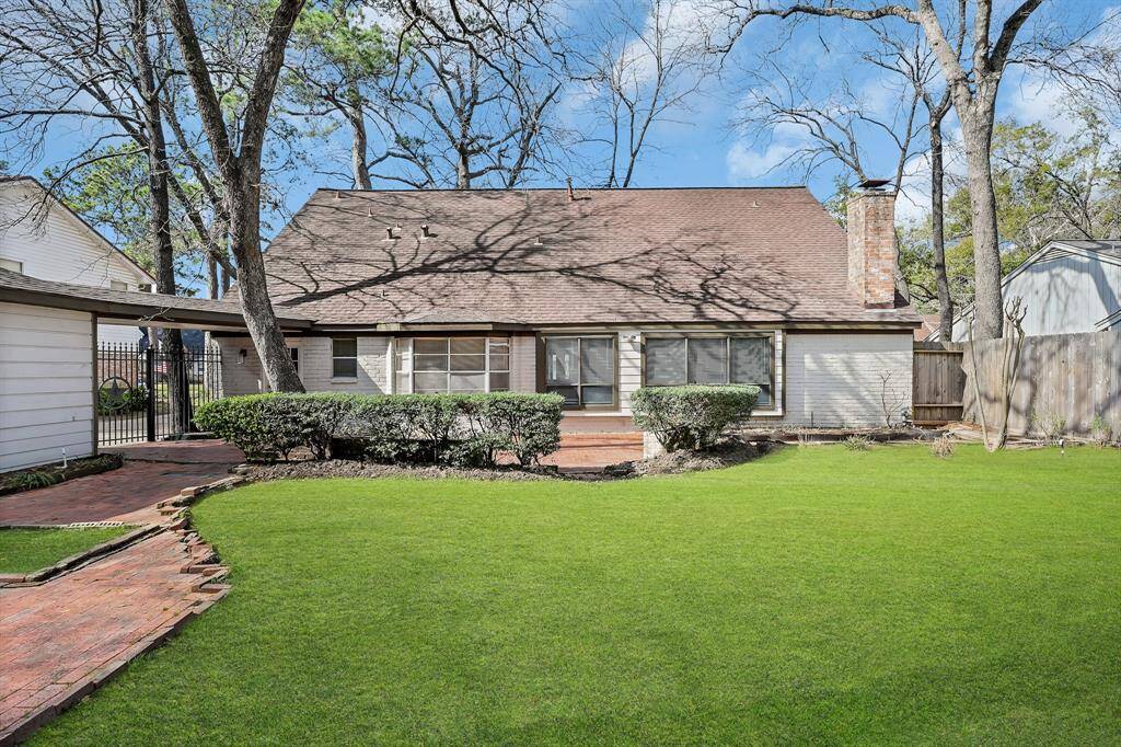 Charming home with a spacious, well-maintained backyard featuring lush grass and mature trees. The exterior includes a brick pathway and a cozy chimney, offering a serene and welcoming atmosphere. Perfect for outdoor relaxation and entertaining.