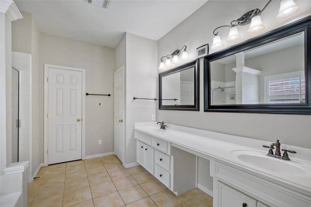 THE PRIMARY BATHROOM FEATURES A DUAL-SINK VANITY WITH AMPLE CABINETS AND COUNTER SPACE.