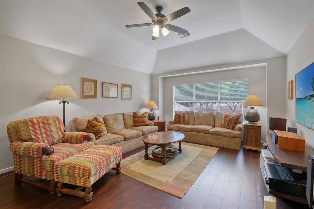THE UPSTAIRS GAMEROOM OFFERS A SPACIOUS RETREAT WITH VAULTED CEILINGS, LARGE WINDOWS, AND RICH WOOD FLOORS.