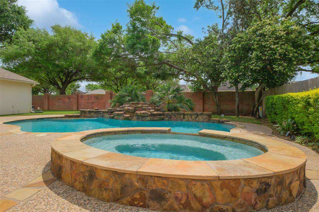 MAKE A SPLASH IN THIS STUNNING BACKYARD FEATURING A RESORT-STYLE POOL, SOOTHING SPA, AND TROPICAL VIBES.