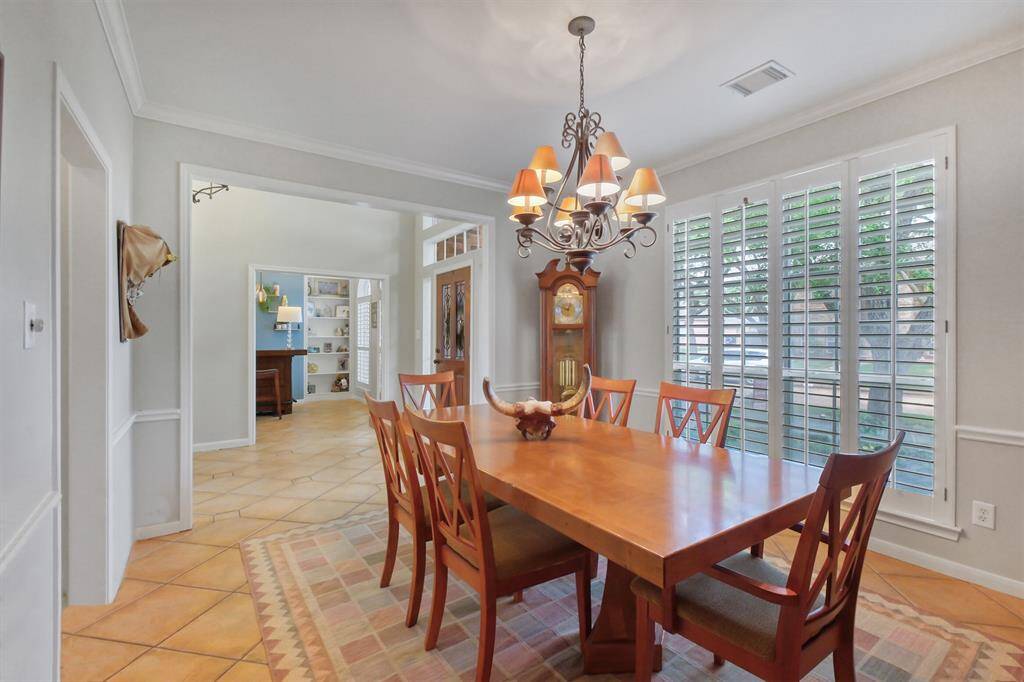 ENJOY SEAMLESS FLOW FROM THE DINING AREA TO THE FOYER, SHOWCASING BEAUTIFUL TERRACOTTA TILE FLOORING AND OVERSIZED WINDOWS WITH PLANTATION SHUTTERS.