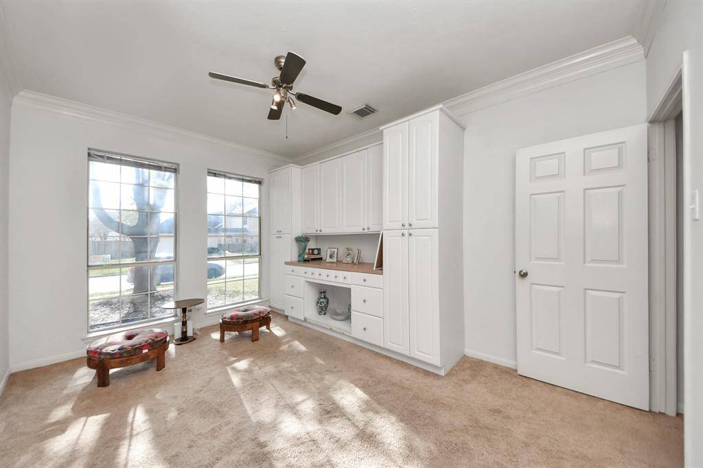 French doors open to this private study, including a built-in desk with plenty of storage space. Other features include crown, neutral paint colors and a ceiling fan.