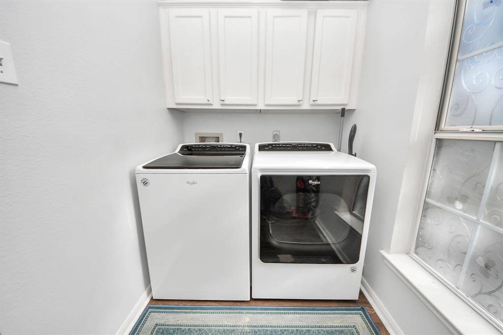 Cheerful laundry has cabinets above for more storage.