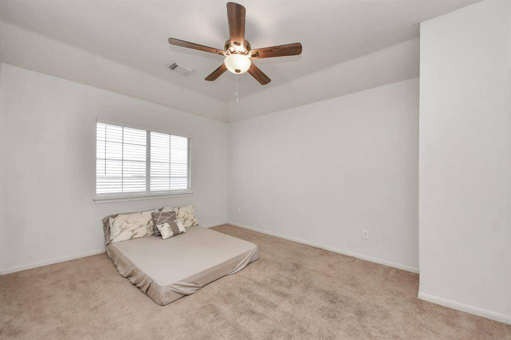 Third guest bedroom upstairs with ceiling fan, overlooks backyard.