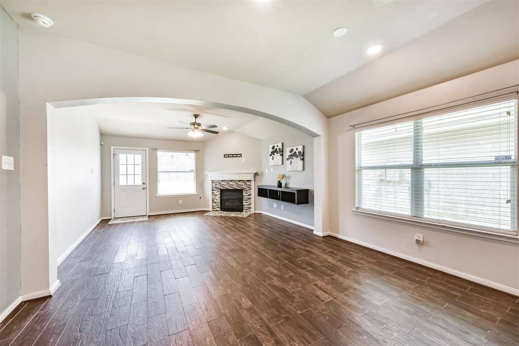 View from dining area into the living room with windows that flood the open space with abundance of natural light, creating a warm and inviting atmosphere. Notice the wood like tile throughout the entire home.