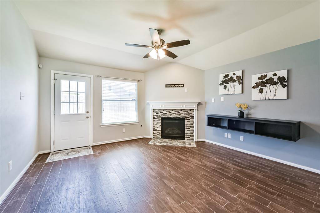 Close view of living room with a gas fireplace for cozy nights. Stylish floating shelf for decor and easy storage solutions. Backyard door recently replaced in April 2025.