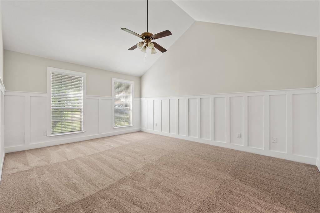 Large primary suite with board and batten walls, high ceiling and en-suite bathroom.