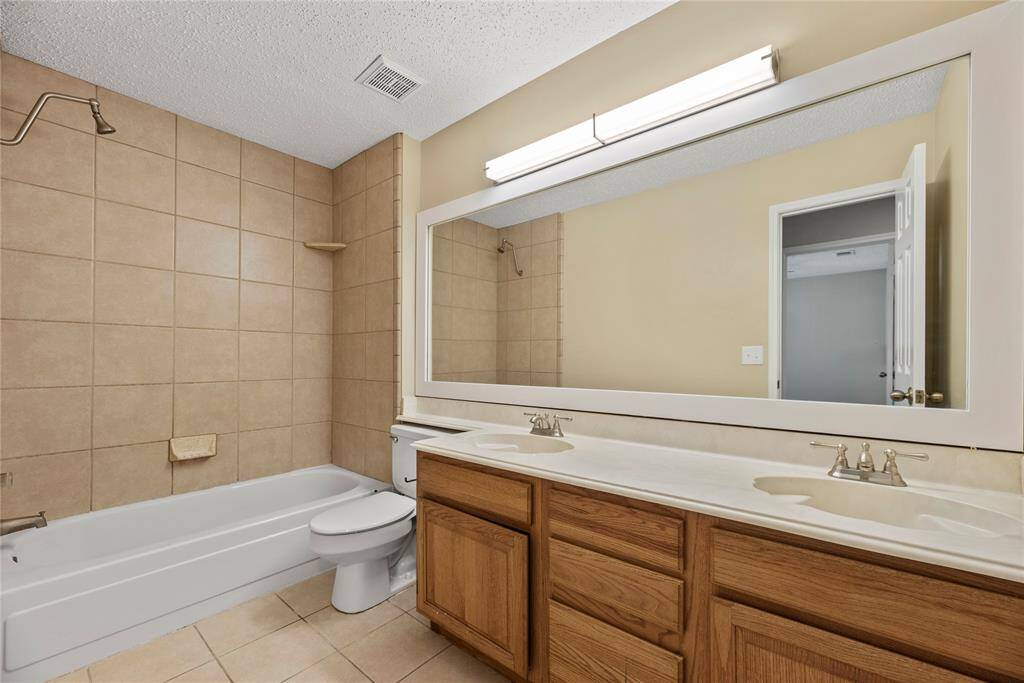 Upstairs full bathroom with a dual sink vanity and tub/shower combination.