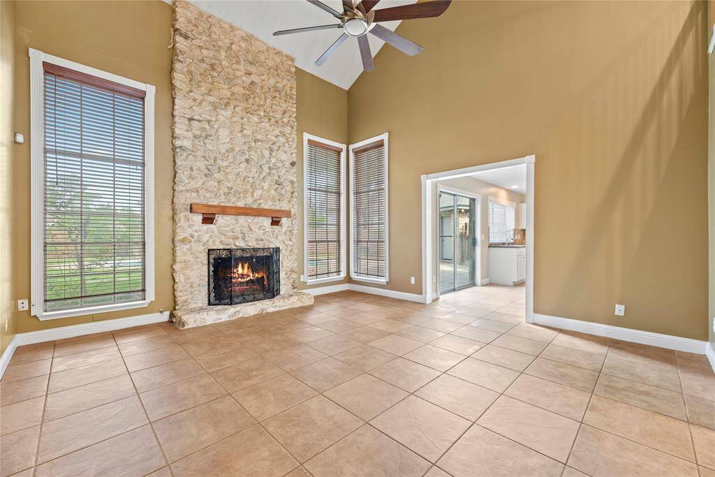 Spacious family room with a 2-story ceiling, ceiling fan and cozy fireplace with stone surround.