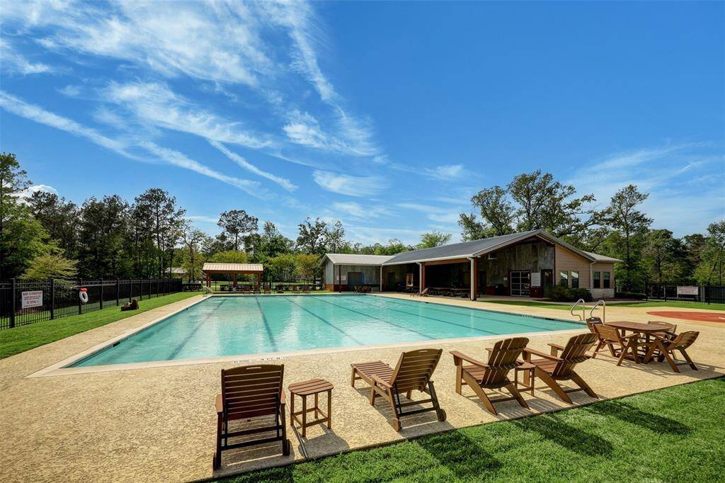 Spacious community pool with lounge chairs, surrounded by greenery High Meadow Estates is known for. There's a clubhouse nearby, perfect for relaxation and social gatherings.
