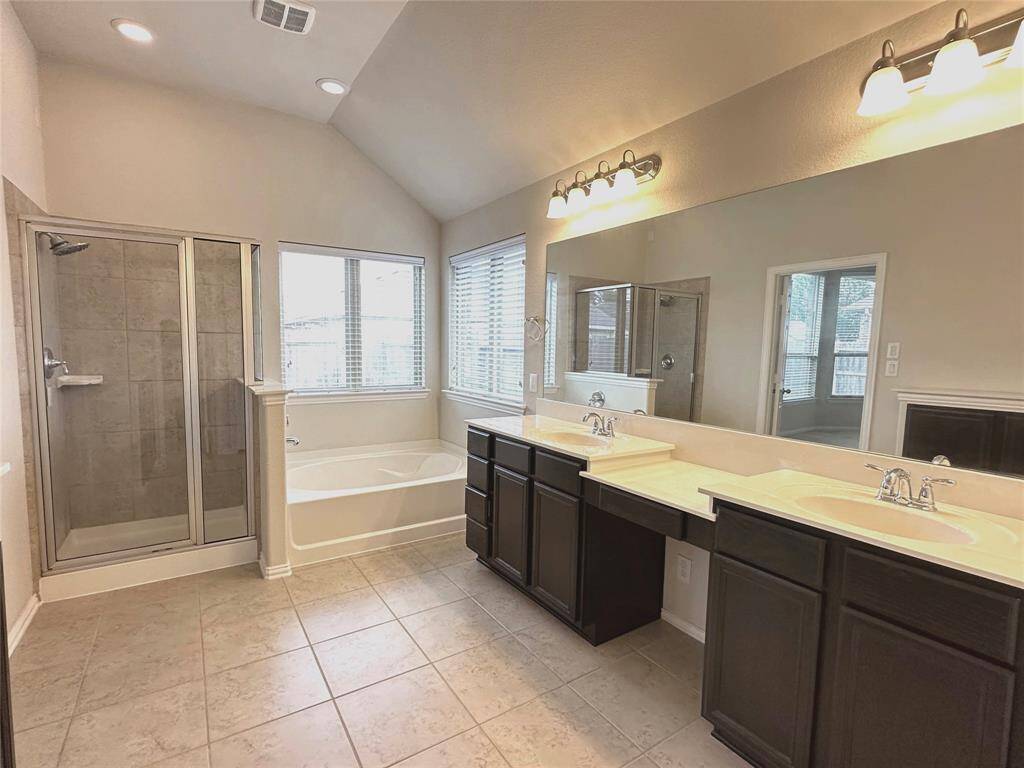 A master bathroom with double sinks, a separate bathtub, and a shower.