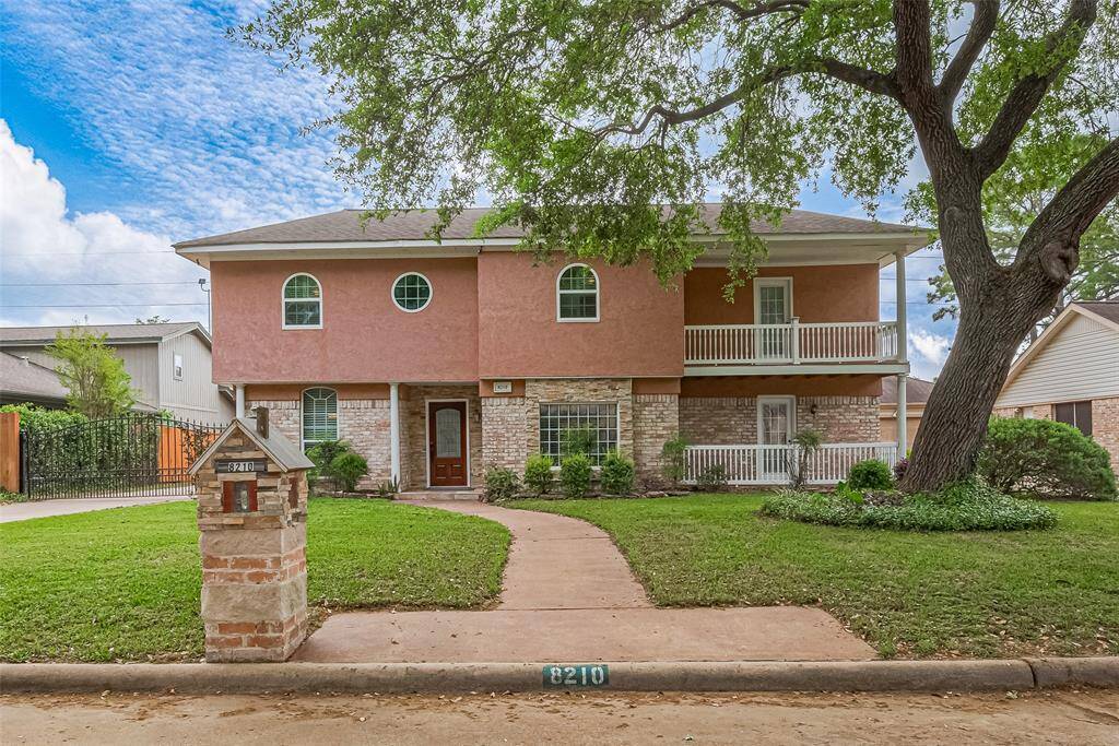 Welcome to 8210 Bo Jack Drive! This stunning two-story home greets you with classic charm and striking curb appeal. The blend of soft stucco and brick accents, oversized arched windows, and double front porches create a warm and welcoming façade. The curved walkway and mature trees frame the home beautifully. Huge shade tree