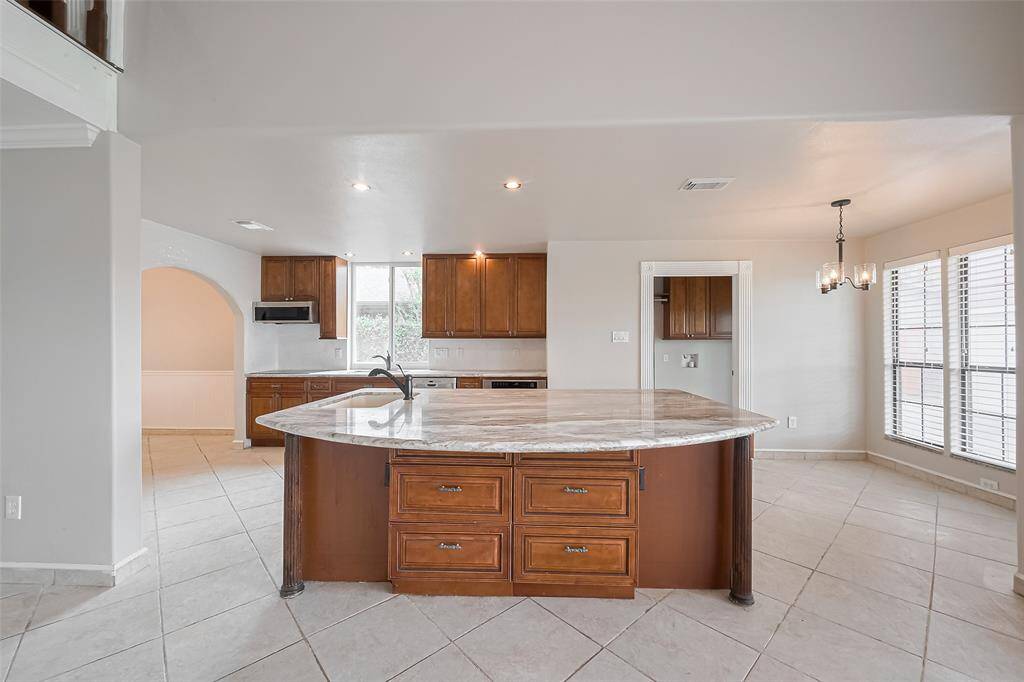 The heart of the home features an expansive granite island with ample prep space, rich wood cabinetry, and elegant pendant lighting. This kitchen was designed with both function and flow in mind, offering plenty of room for gathering.