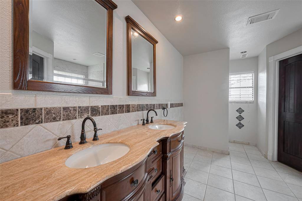 This dual vanity setup offers plenty of space and storage with beautifully detailed cabinetry and an extended granite counter—perfect for morning routines.