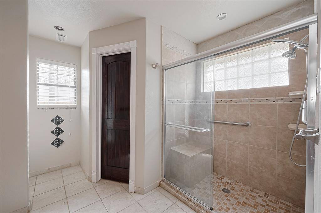 Enjoy the spacious walk-in shower with built-in bench, glass enclosure, and tile surround. A glass block window provides natural light while maintaining privacy.