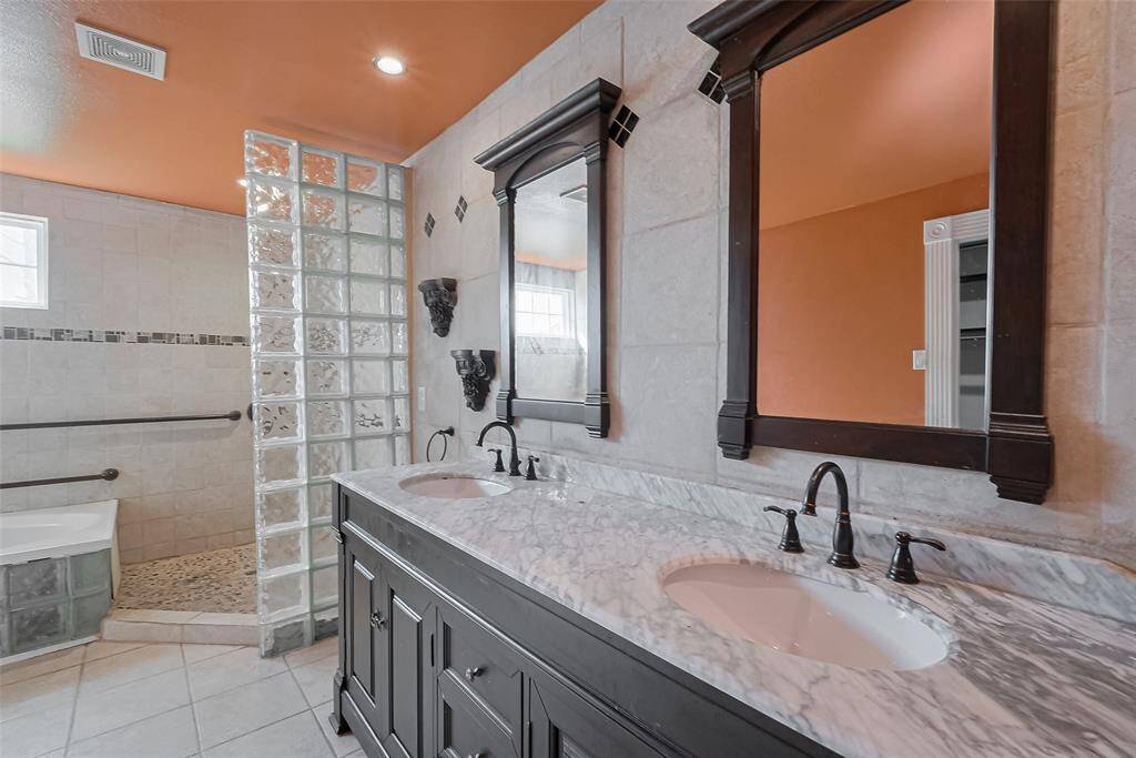 Stylish and dramatic, this bathroom offers dual vanities with marble countertops, matching framed mirrors, and contemporary lighting—making it a standout secondary suite.