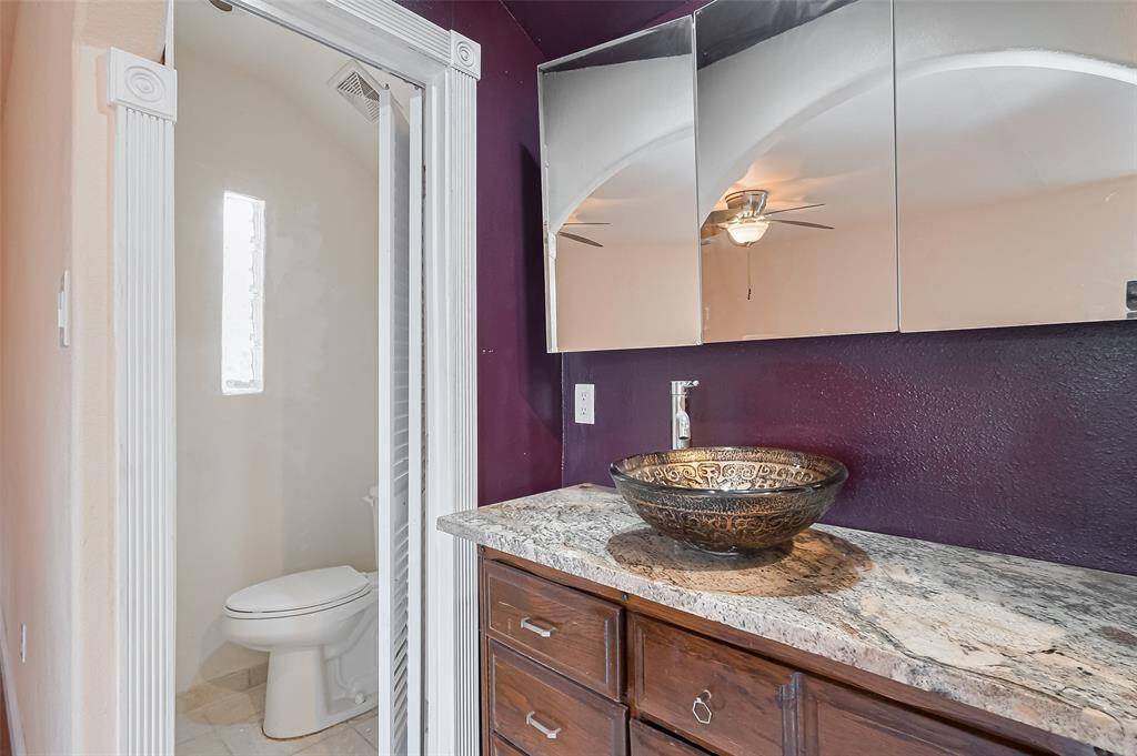 4th bath upstairs with stylish vessel sink and granite vanity features rich-toned cabinetry and a custom mirror cabinet, offering both form and function.