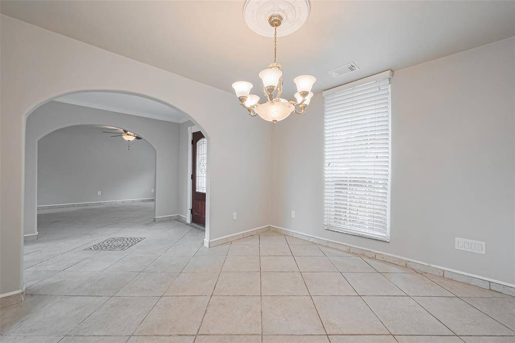 The formal dining room is enhanced by chair rail molding, a classic chandelier, and large windows offering ample natural light. The neutral color palette and tile flooring provide a timeless backdrop for entertaining.