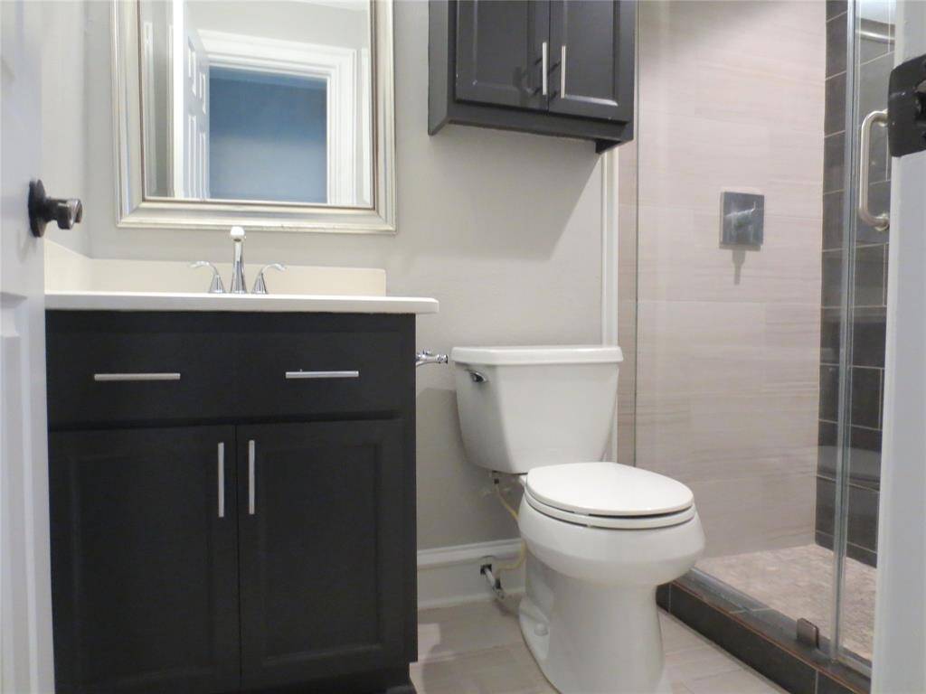 This bathroom features a modern design with a sleek vanity, a large mirror, and a glass-enclosed shower. The neutral color palette provides a clean and inviting atmosphere.