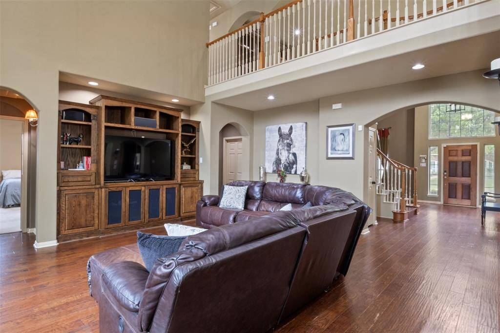 This thoughtfully designed living room blends openness with warmth, offering seamless access to the entryway, kitchen, and primary suite. The custom built-ins, soaring ceilings, and rich hardwood floors make it a perfect hub for relaxation, entertainment, and everyday living.