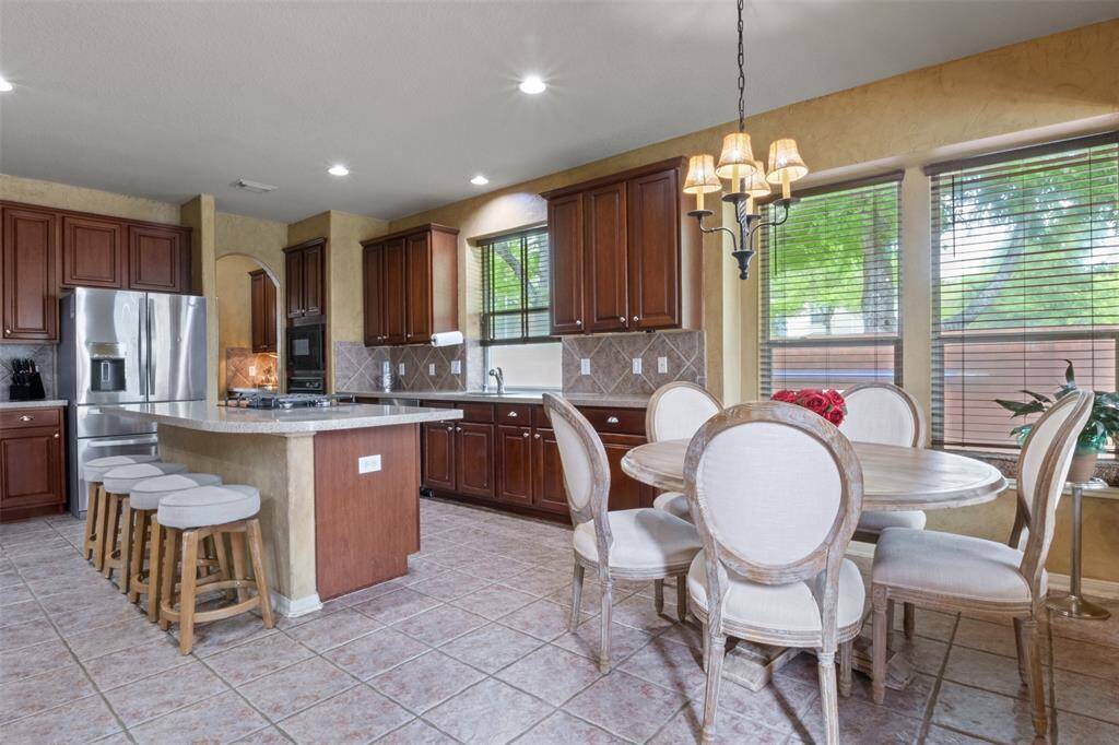 Gather around the island or enjoy casual meals in the sunlit breakfast nook, framed by oversized windows that invite the outdoors in. With stainless steel appliances, abundant cabinetry, and timeless tile floors, this kitchen is as practical as it is welcoming.