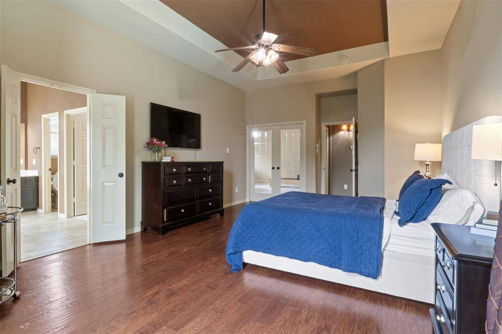 The primary suite continues to impress with rich hardwood flooring, a dramatic tray ceiling, and private access to a luxurious ensuite bath. Spacious and serene, this retreat offers a harmonious blend of style, comfort, and functionality.