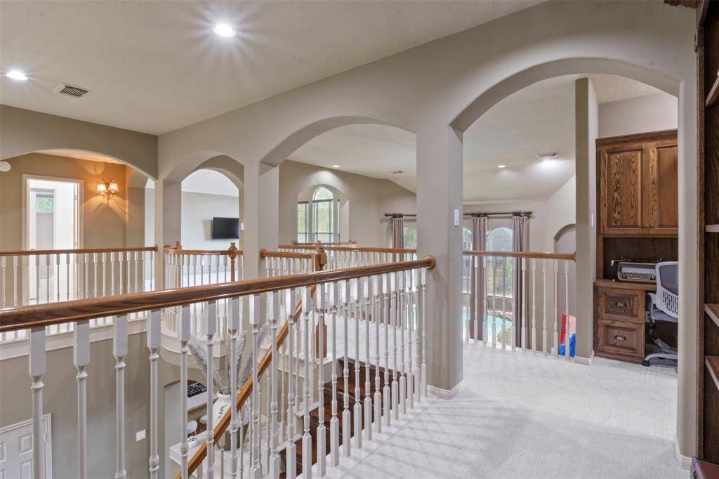 The upstairs landing offers architectural elegance with graceful arches, open sightlines, and a built-in desk tucked away for quiet productivity. Overlooking both the grand foyer and living area, this space blends beauty and function effortlessly.