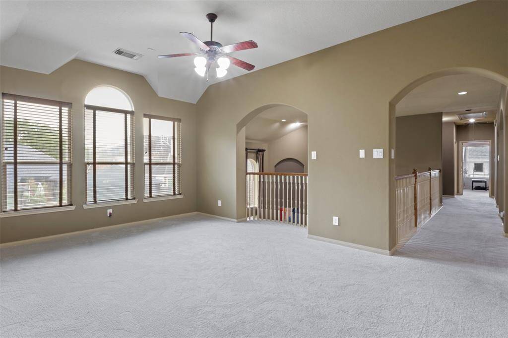 Framed by arched entries and sunlit windows, the upstairs game room offers generous space for recreation or relaxation. The adjoining hallway leads to additional bedrooms and flex areas, creating a layout that supports both privacy and connection.