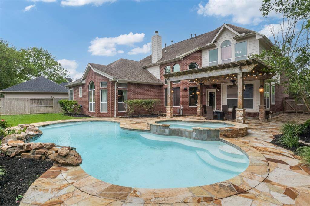 Bask in the beauty of this resort-style backyard—featuring a sun-soaked swimming pool, elevated spa with cascading water feature, and a spacious pergola-covered patio ideal for outdoor dining and entertaining.