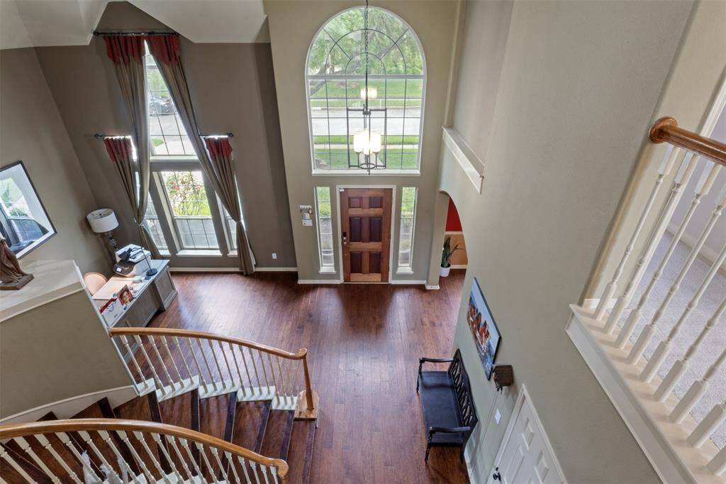 From above, the grand foyer showcases its impressive scale—highlighted by rich wood flooring, a graceful curved staircase, and a dramatic two-story arched window that fills the space with soft, natural light. A true statement entrance that sets the tone for the rest of the home.
