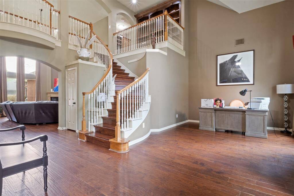 The grand curved staircase creates an unforgettable architectural focal point, while the soaring ceilings and open sightlines invite a sense of connection throughout the home. Whether greeting guests or enjoying a quiet moment in the adjacent study nook, this space radiates both elegance and functionality.